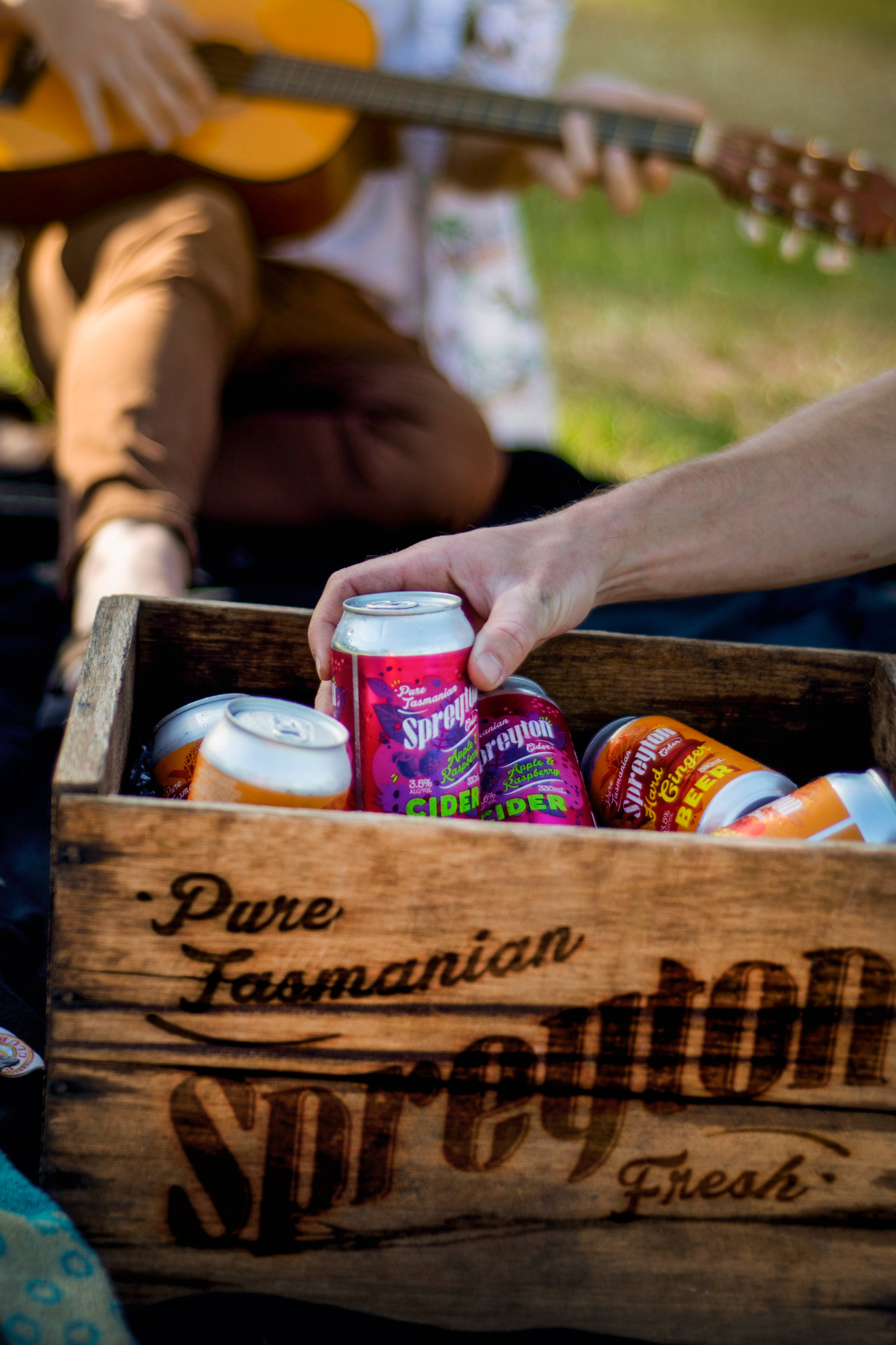 Hand picking a can of Spreyton Cider out of a wooden box branded ‘Pure Tasmanian Spreyton Fresh’. Photo: Spreyton Fresh.